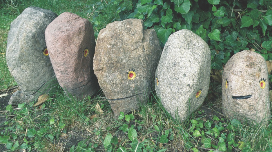 Ogrodu pilnują kamienne głowy zrobione z dużych kamieni i pomalowane mrozoodpornymi farbami