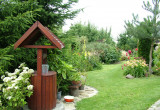 Jeden z widoków, jaki wyłania się za magicznym wejściem, lewa strona ogrodu, ze studnią i wieloma rabatami kwiatowymi