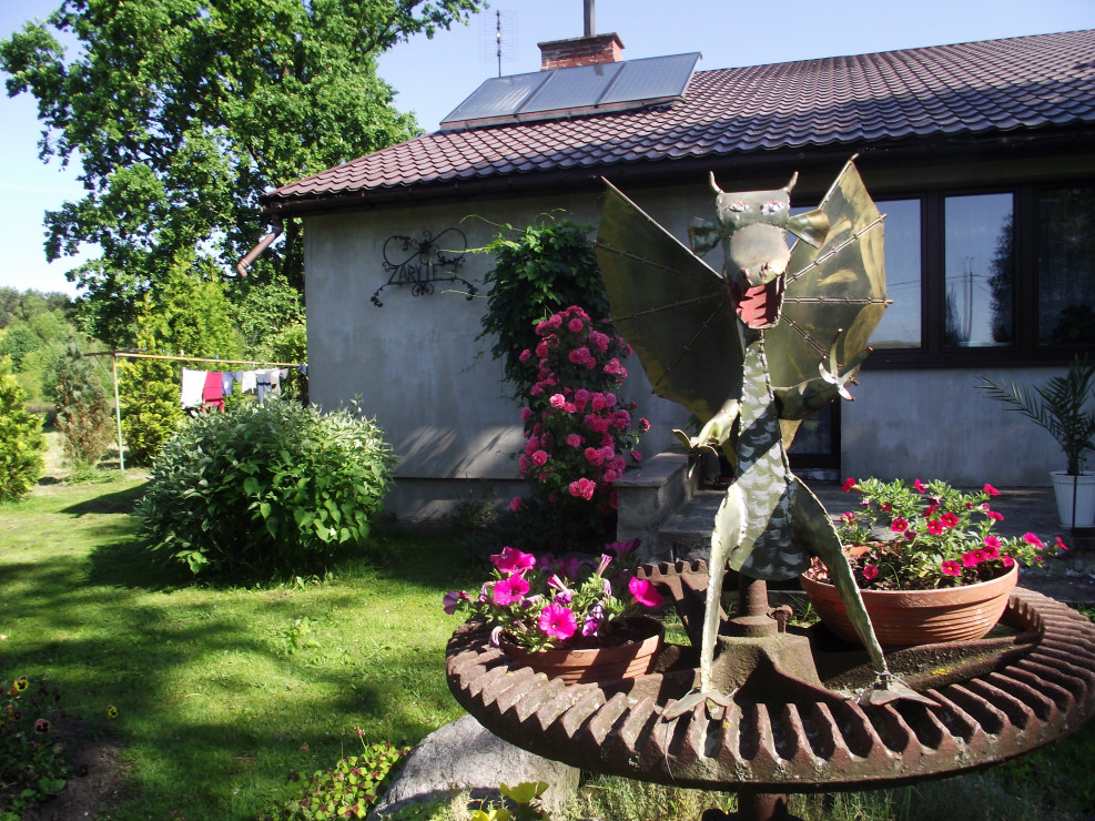 Odwrócone koło kieratu tworzy kwietnik nad którym góruje smok wykonany własnoręccznie przez mojego męża.