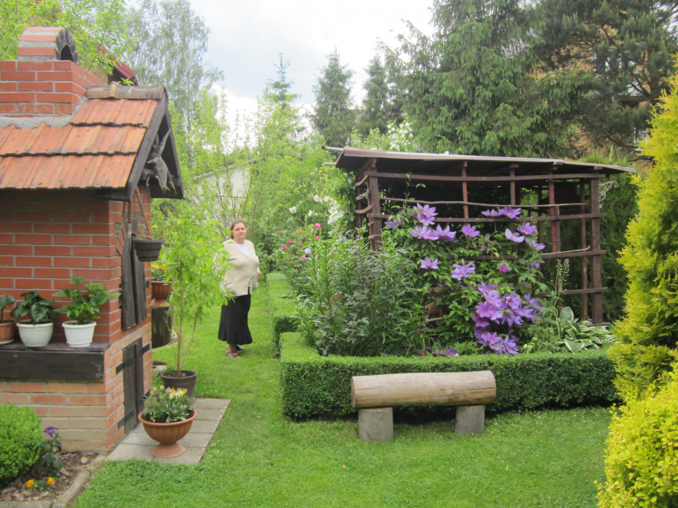 Mama Maria w  ogrodzie koło niewielkiej altanki i grilla zrobionego przez tatę Jana.