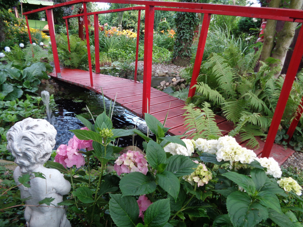 Woda w ogrodzie jest ważnym elementem, dlatego stworzyliśmy w południowej zachodniej stronie oczko połączone z mostkiem i fontanną, otoczone głazami kamiennymi i trawami ozdobnymi i lilowcami.