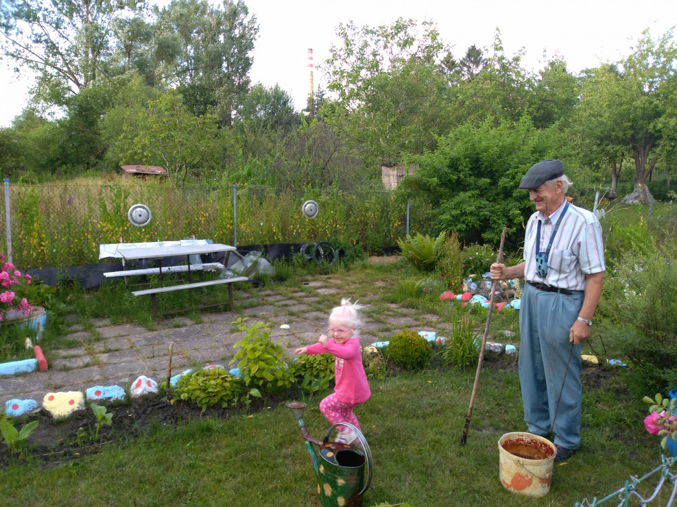 Dziadek Stefan pokazuje Karolince jak podlewać rośliny